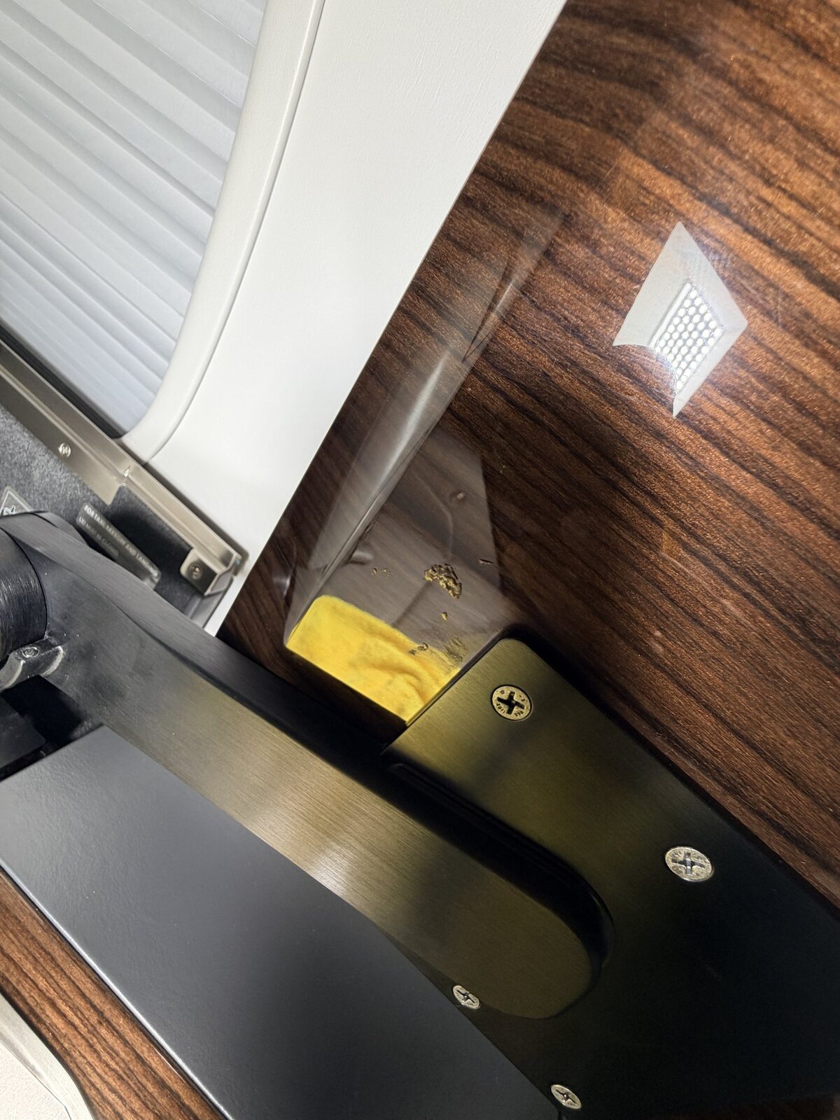 Before: debris buildup beneath a pop-out tray table on Challenger 350 wood veneer surface