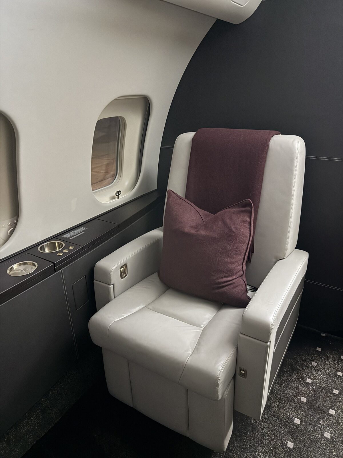 After: private cabin seating reset with light leather and dark trim on Global 5000