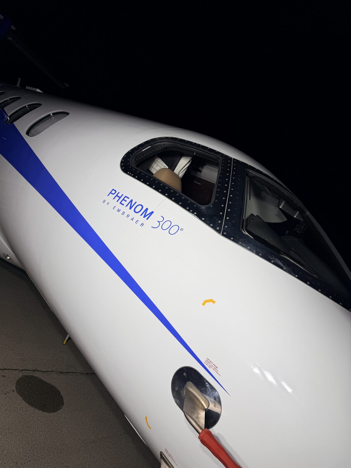 Embraer Phenom 300 wing and fuselage under ramp lighting at Chicago Midway at night