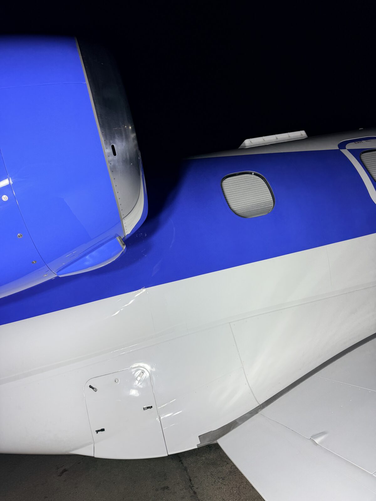 Phenom 300 fuselage and wing root detail showing blue and white paint transition at MDW
