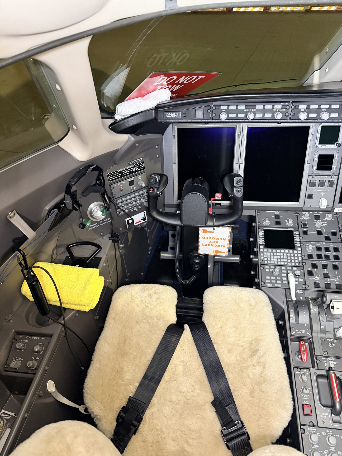 Bombardier Challenger 300 captain side cockpit with sidestick, PFD displays, and sheepskin seat cover after detailing at PWK