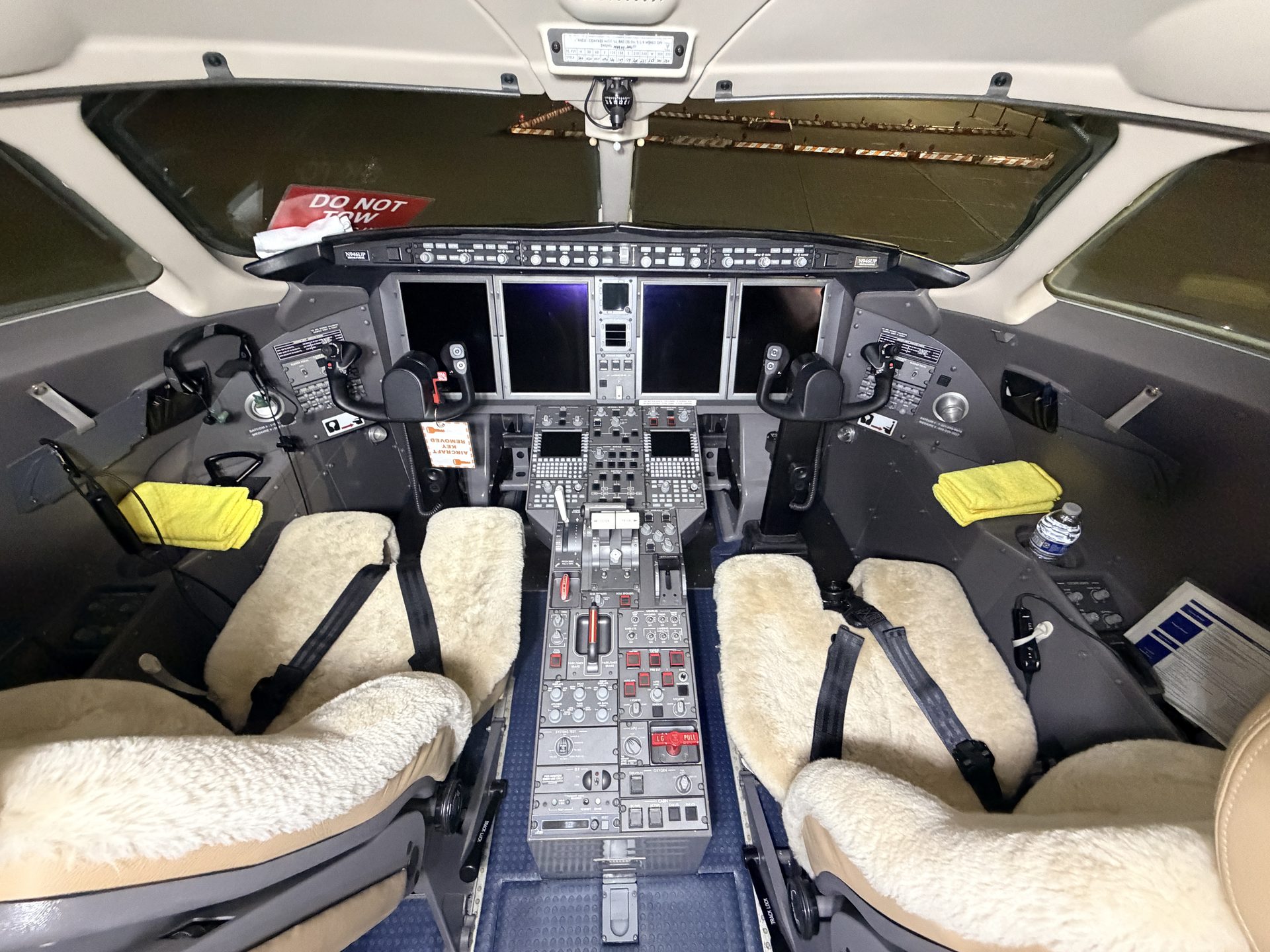 Bombardier Challenger 300 full cockpit flight deck with sheepskin seat covers, throttle quadrant, and instrument panels after detailing at PWK