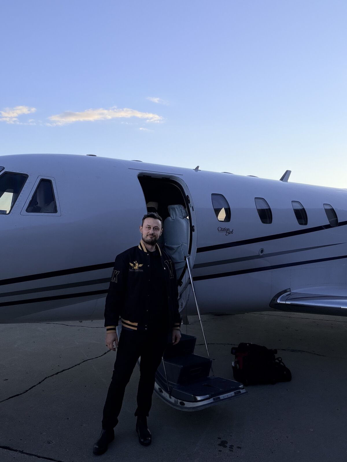 The Polished Hare aviation detailer standing in front of Cessna Citation Excel wearing branded jacket at dusk on airport ramp