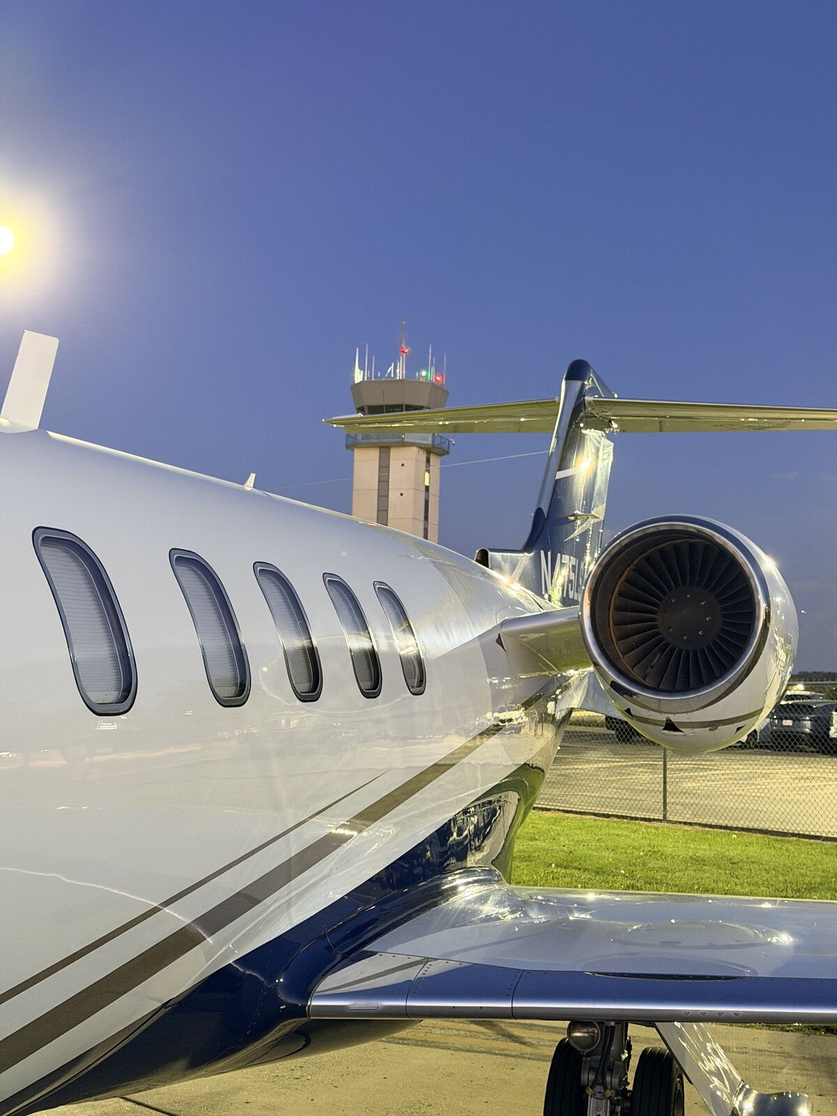 Cessna Citation Excel engine nacelle and wing viewed from fuselage side with airport control tower in background after exterior wash
