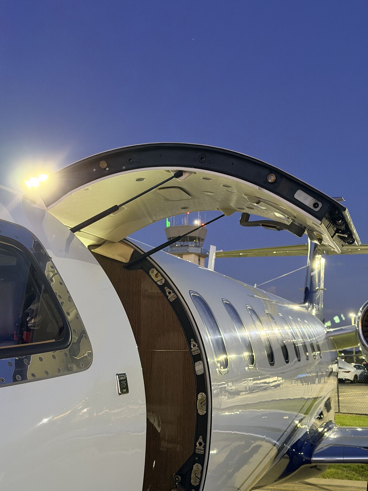 Cessna Citation Excel entry door open at night showing door mechanism and polished fuselage under ramp lighting