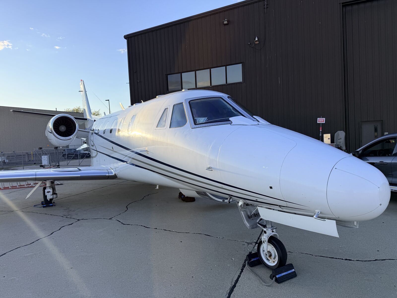 Cessna Citation Excel nose and fuselage quarter view parked on ramp near hangar during golden hour after exterior detailing