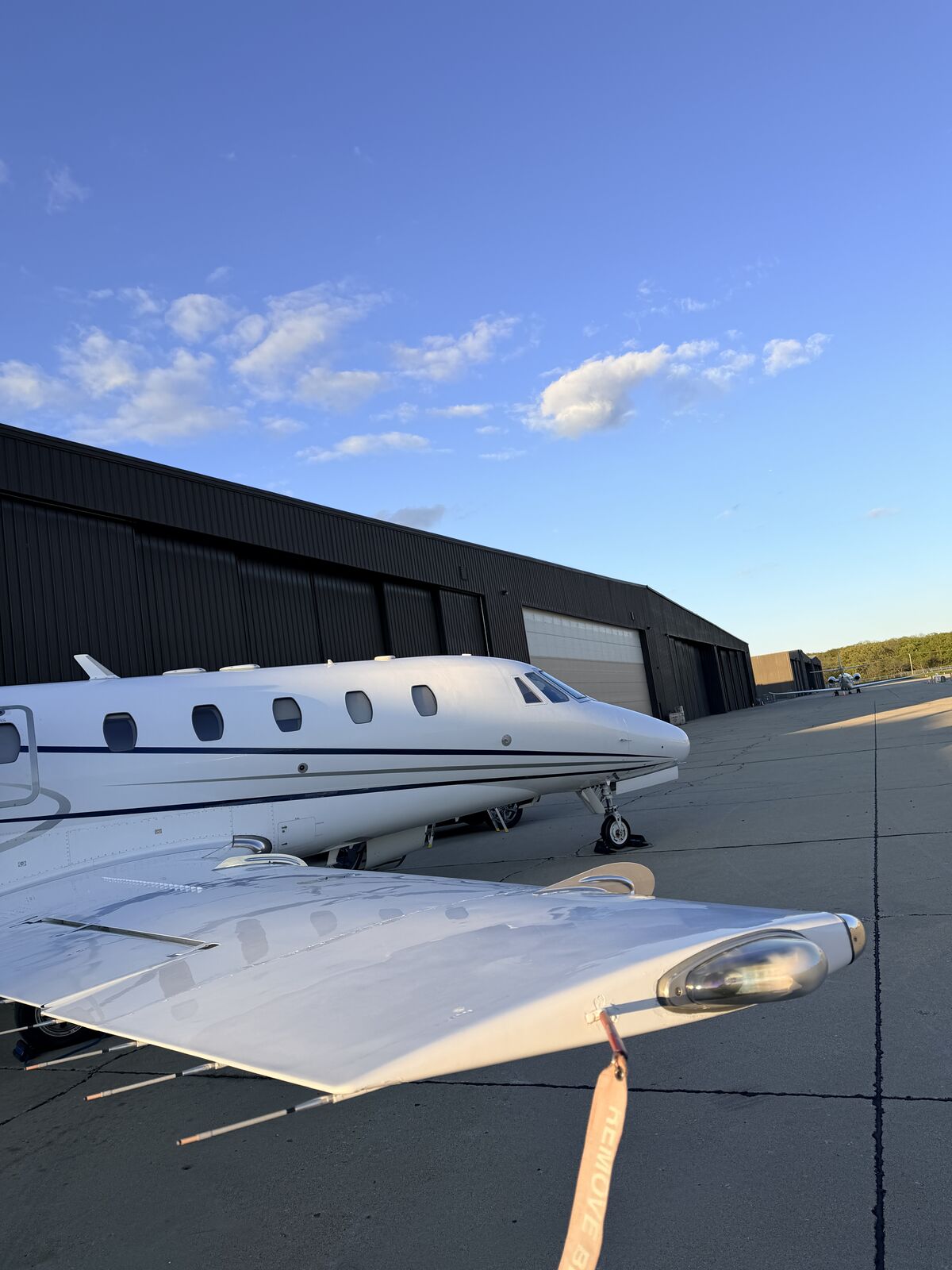 Cessna Citation Excel tail and empennage parked near dark hangar on airport ramp after exterior wash and detail