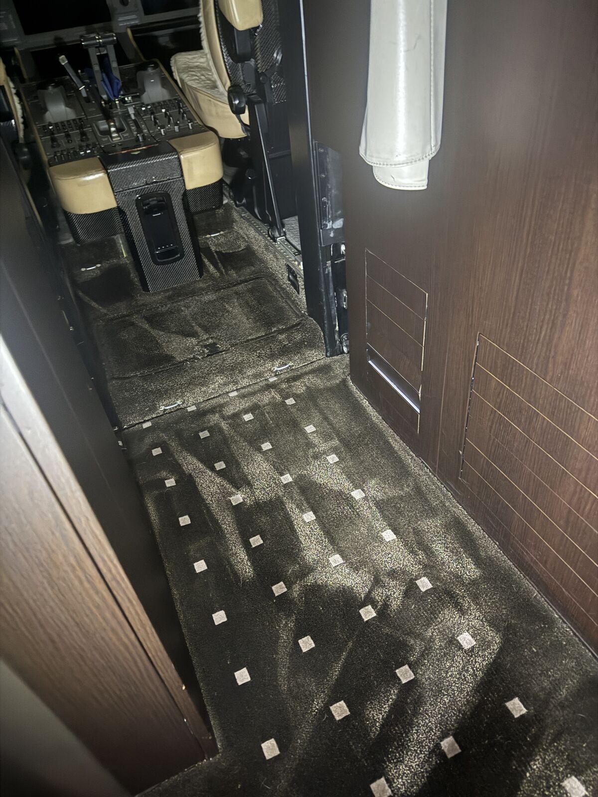 Private jet cabin patterned carpet aisle with diamond pattern and cockpit threshold visible after carpet extraction