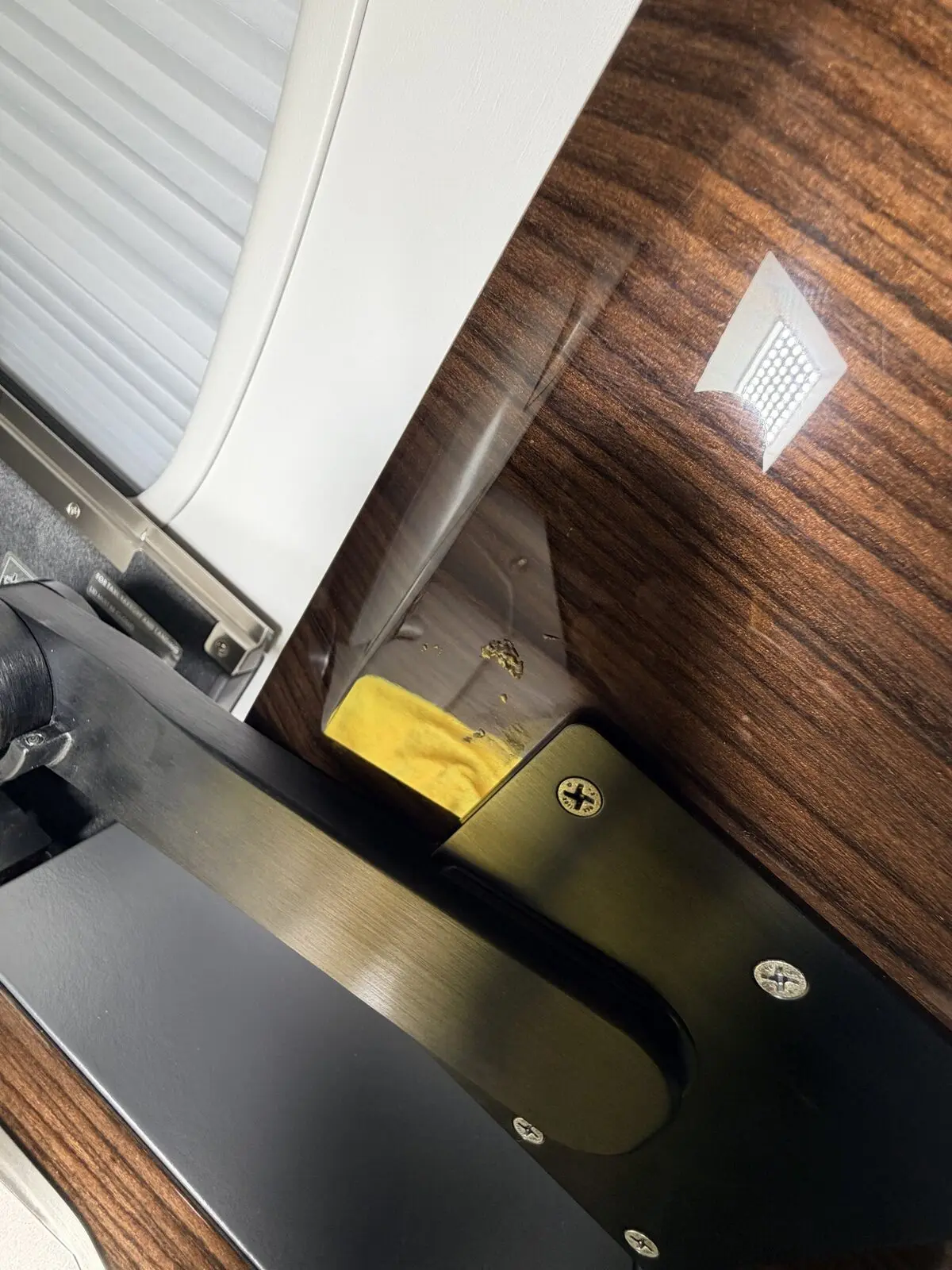 Before: debris buildup beneath a pop-out tray table on Challenger 350 wood veneer surface