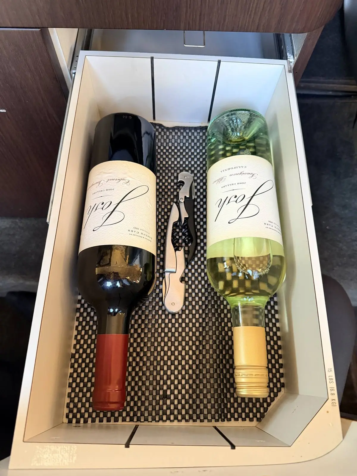 Organized wine service drawer with bottles and corkscrew presented neatly in Cessna Citation X galley