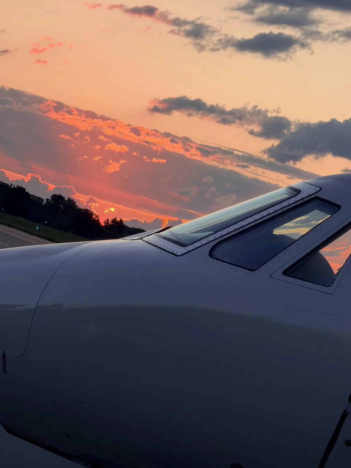 Cessna Citation X nose and flight-deck windscreen reflecting a dramatic orange sunset, polished fuselage free of streaking