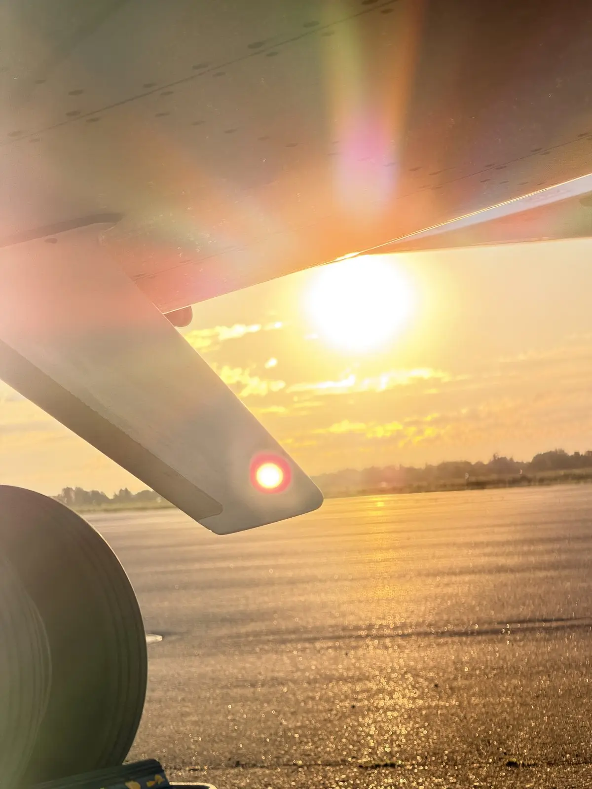 Sun flare beneath the wing and winglet of a Cessna Citation X at golden hour, reflecting off a clean ramp surface
