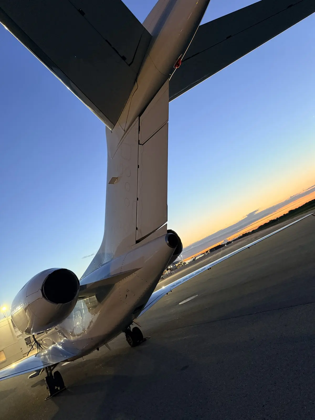 Cessna Citation X empennage, T-tail, and aft engine nacelle at dusk with a sunset horizon behind the ramp