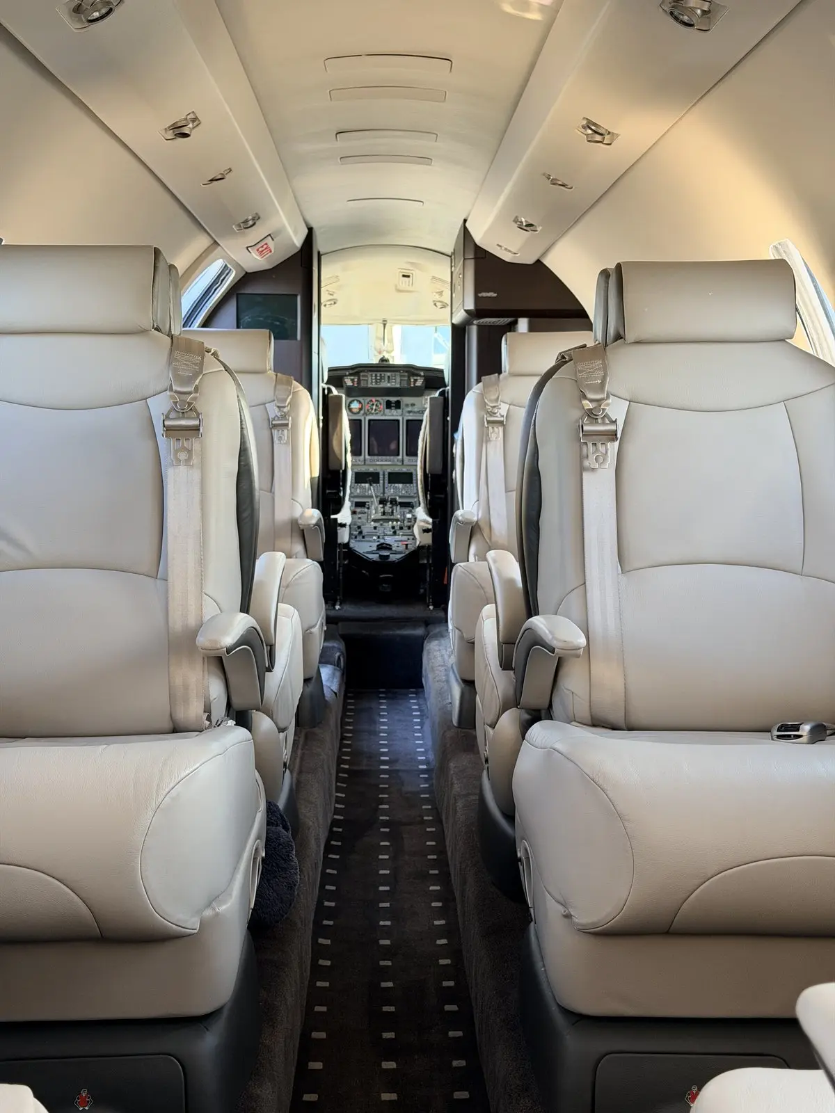 Cessna Citation X cabin after a Level 2 interior detail showing two rows of cream leather club seats, a clean aisle runner, and the lit flight deck forward