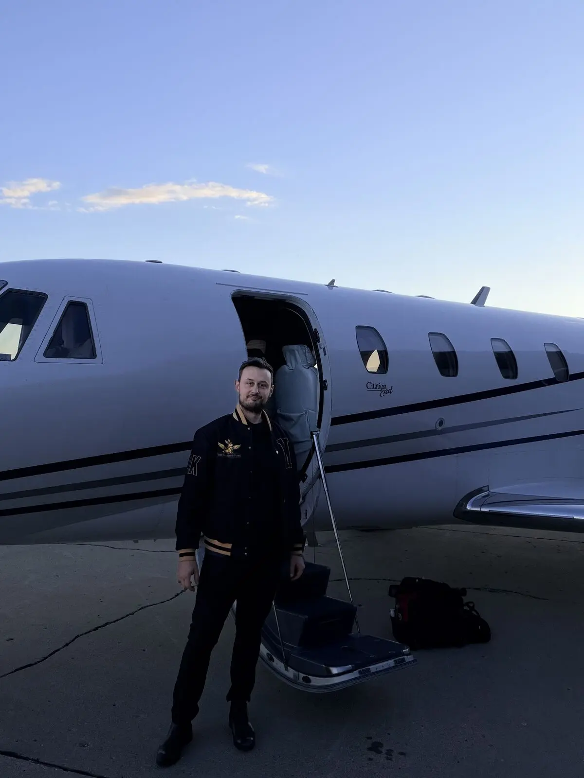 The Polished Hare aviation detailer standing in front of Cessna Citation Excel wearing branded jacket at dusk on airport ramp