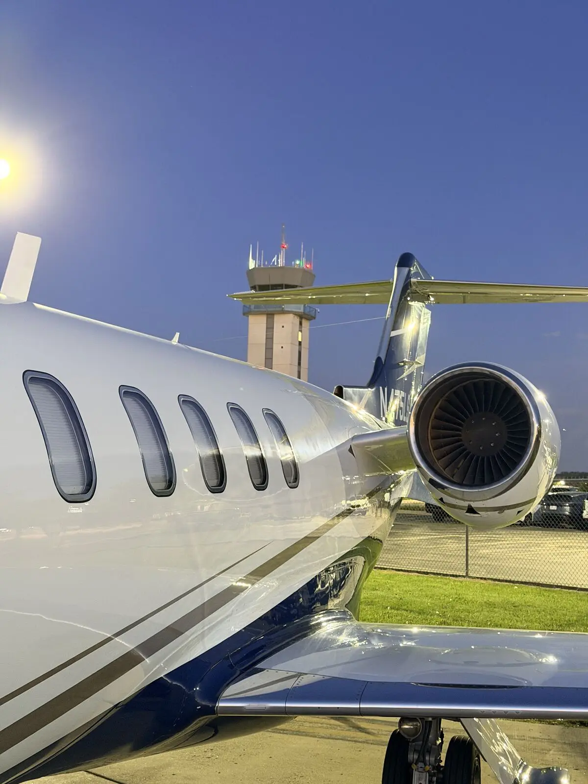 Cessna Citation Excel engine nacelle and wing viewed from fuselage side with airport control tower in background after exterior wash