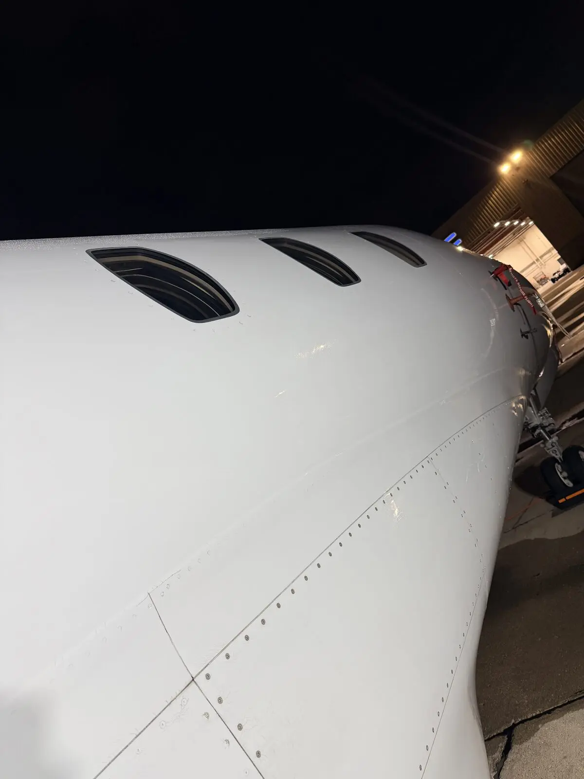 Cessna Citation X fuselage and cabin windows gleaming under hangar lighting after exterior wash at night