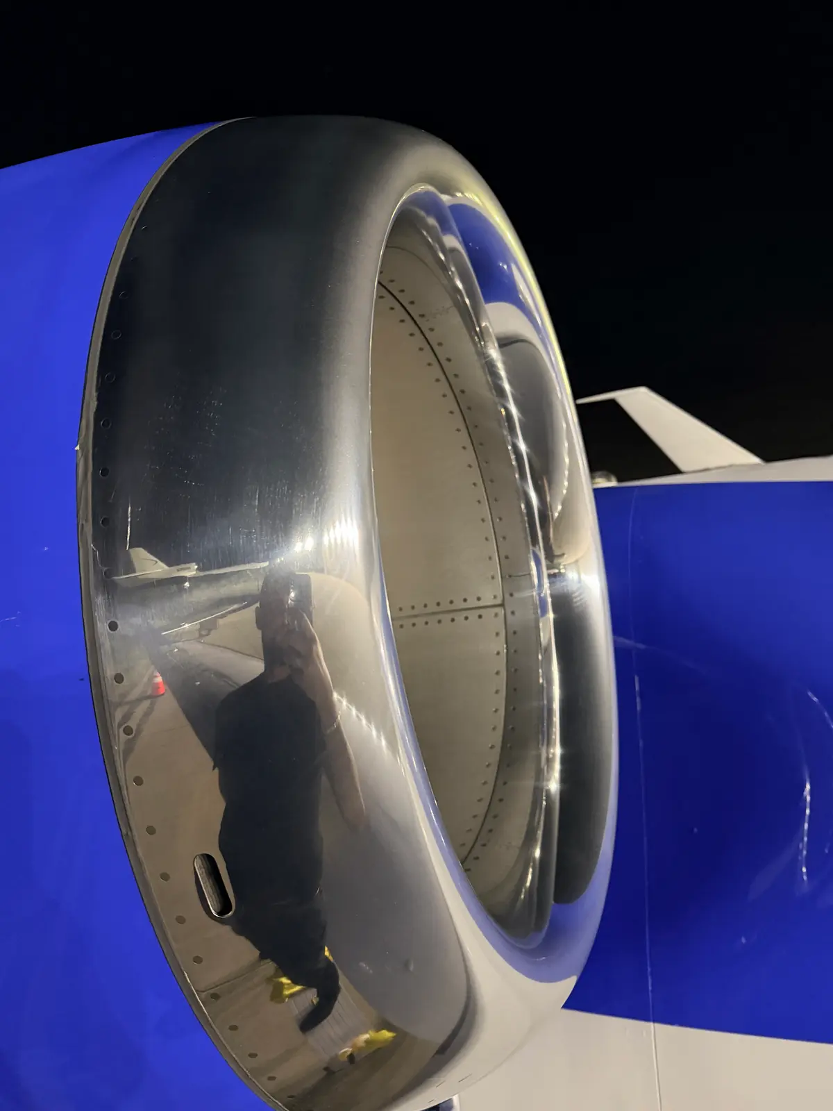 Embraer Phenom 300 polished engine inlet cowl at an angle showing chrome reflection and blue nacelle at night