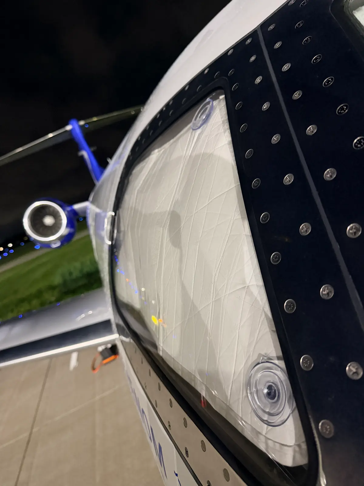 Embraer Phenom 300 clean white nose radome and forward fuselage with nose gear at night after exterior wash