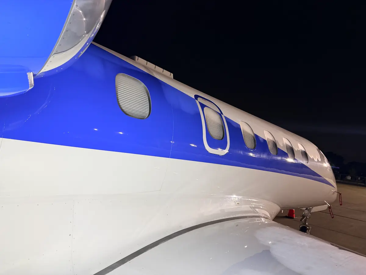 Phenom 300 fuselage cabin windows and over-wing exit cleaned and presented under ramp lighting at night