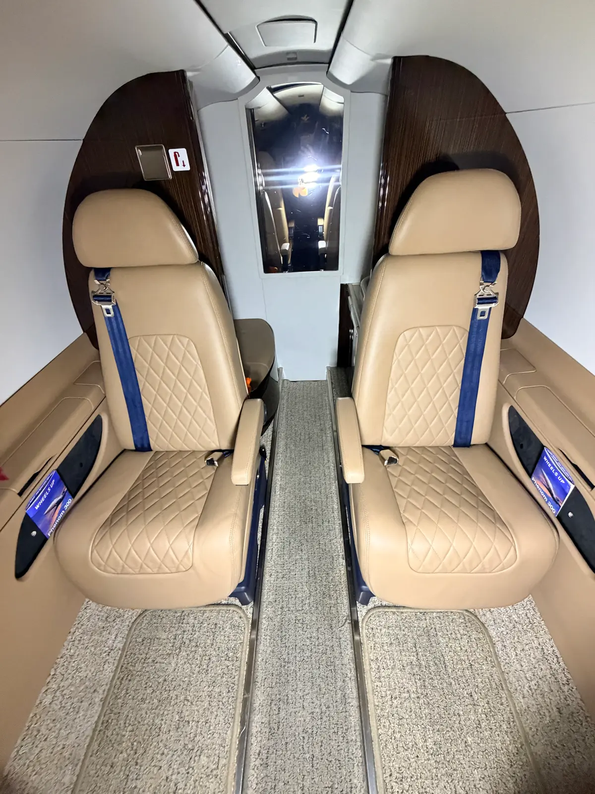 Embraer Phenom 300 cabin club seating both sides of the aisle with quilted tan leather seats and a mirror-polished bulkhead after interior detailing