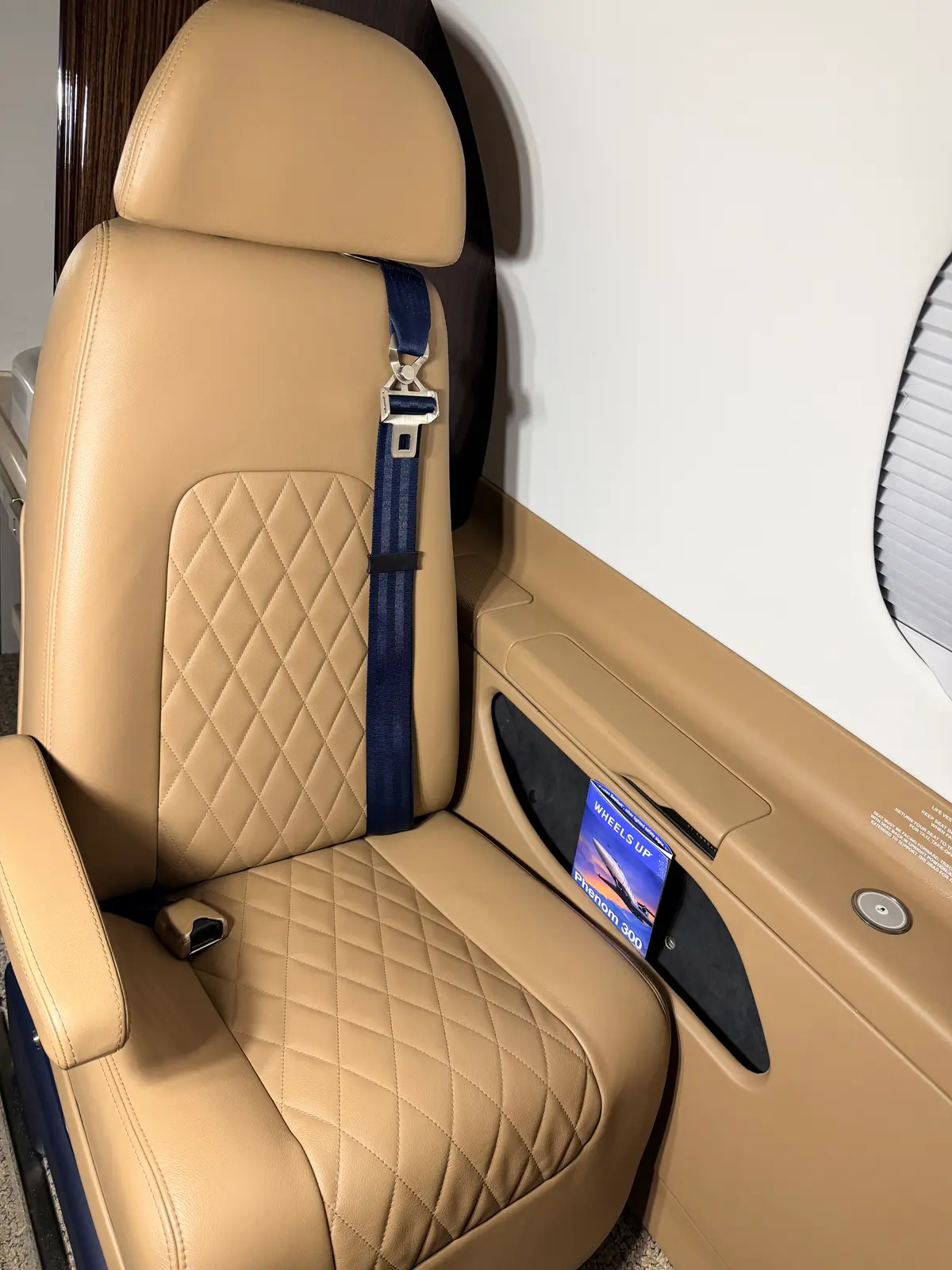 Phenom 300 polished wood console with brushed-metal cupholders and pleated window shade after cleaning